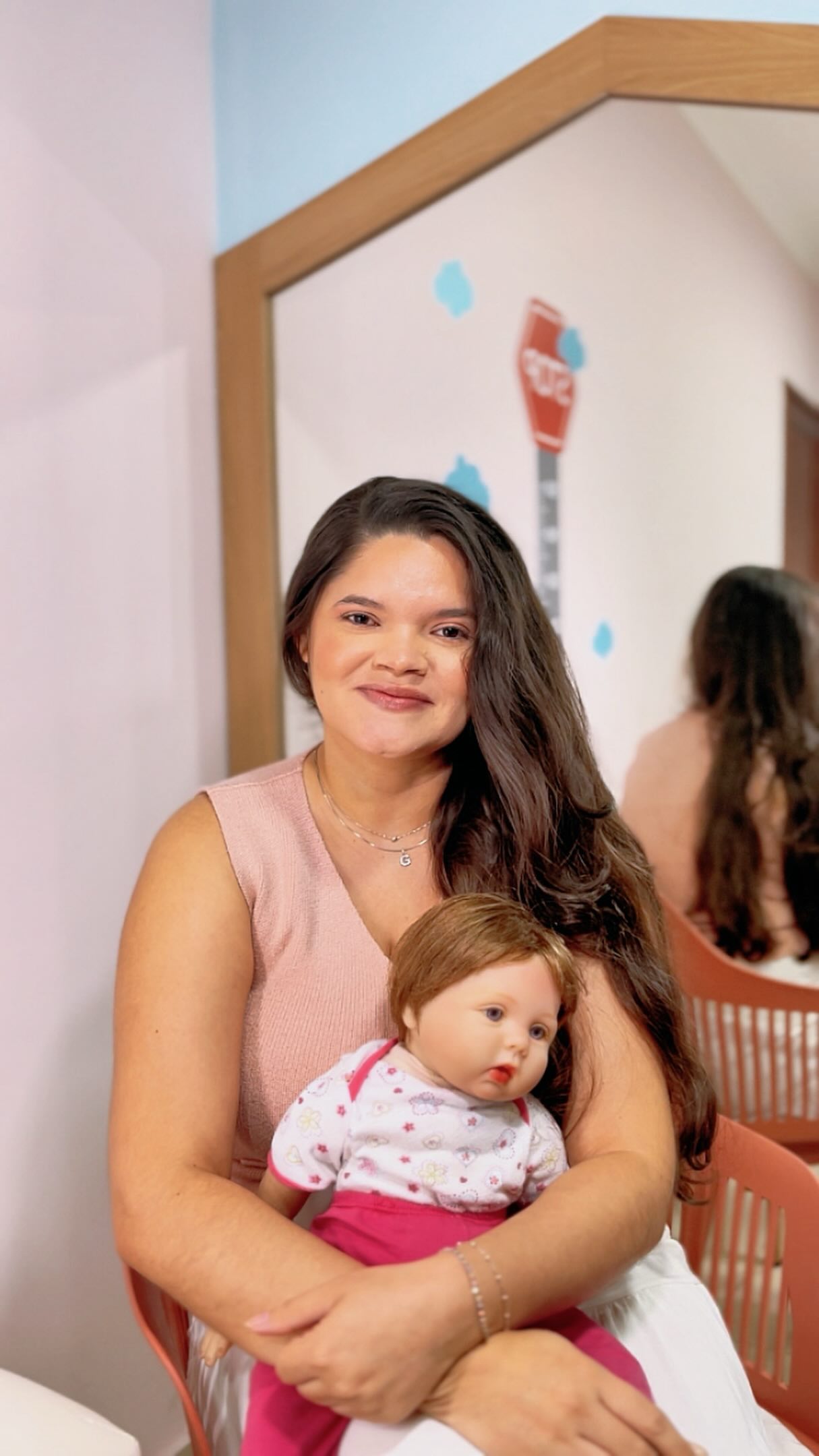 Gleiciane sentada com uma boneca no consultório