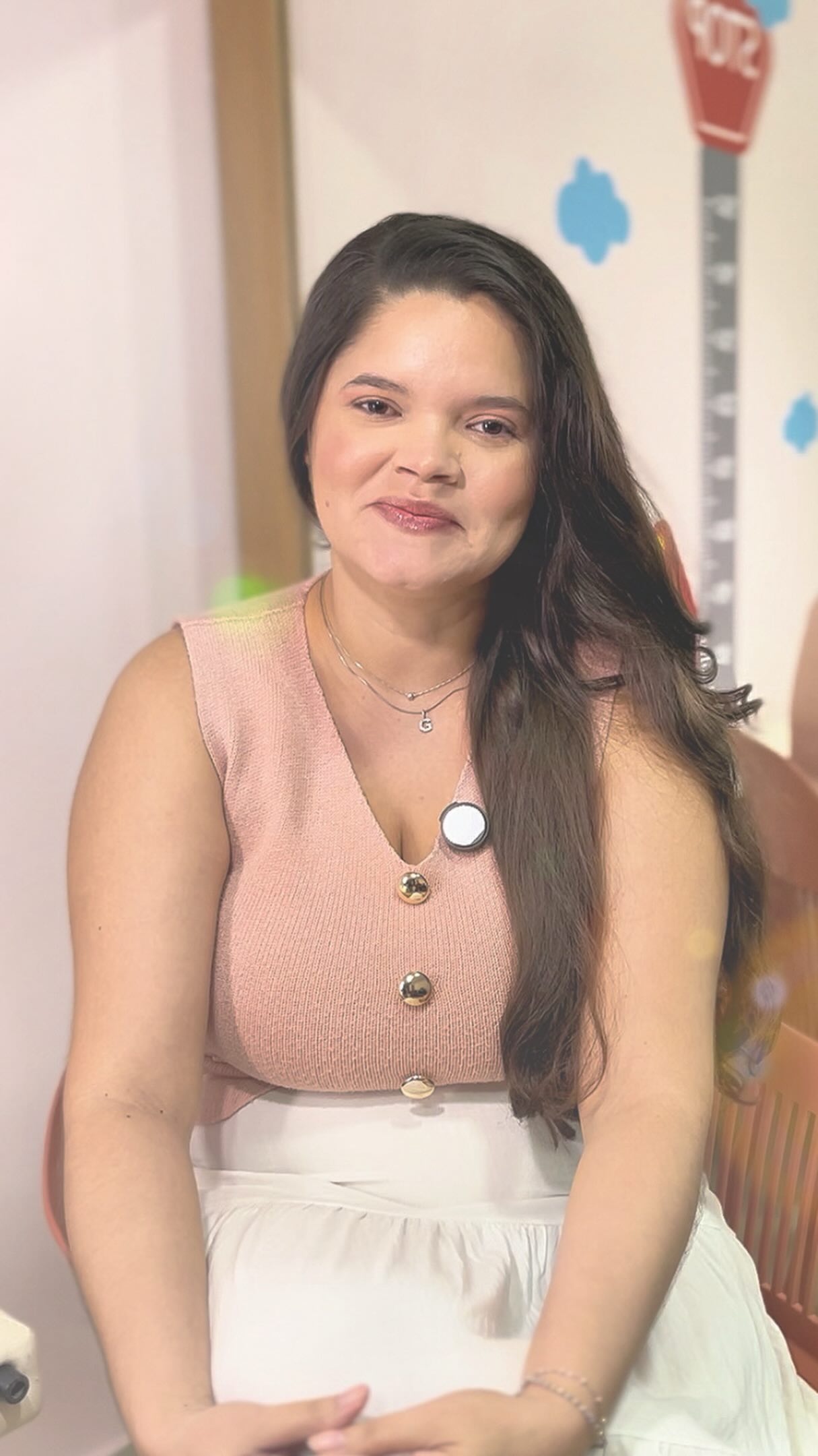 Gleiciane sentada no consultório com blusa rosa